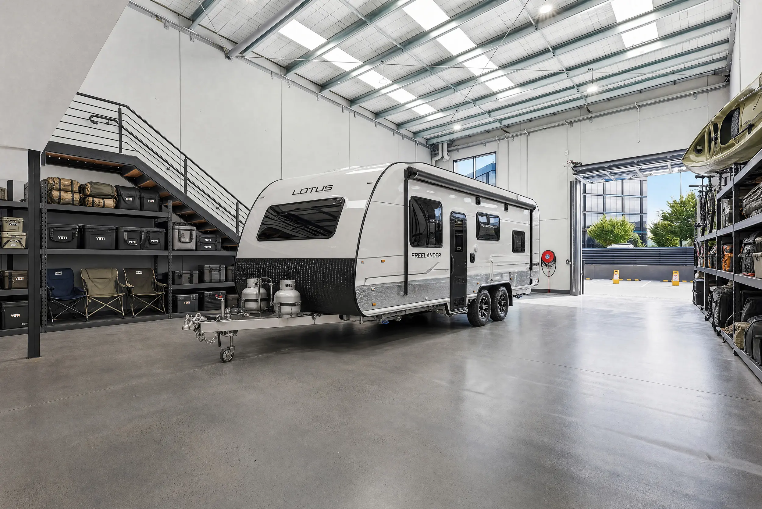 A Jacoah Place tenancy styled for caravan storage, with a touring caravan parked clear of the mezzanine stair and shelving for camping gear